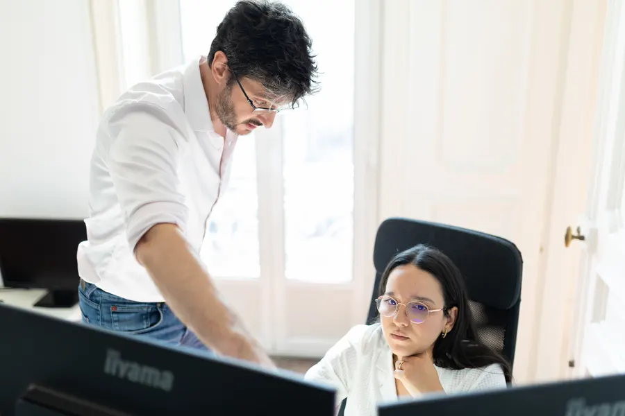 A developer points something out on screen to a colleague